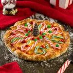 Festive Christmas pizza decorated with candy canes, red and green candies, and a chocolate cone centerpiece.