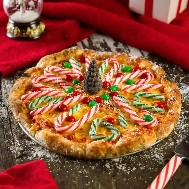 Festive Christmas pizza decorated with candy canes, red and green candies, and a chocolate cone centerpiece.