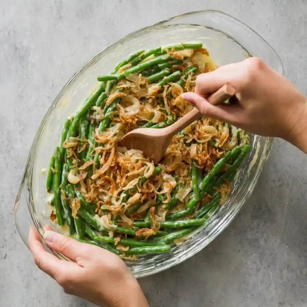 Green beans and caramelized onions sizzling in a stainless-steel skillet.
